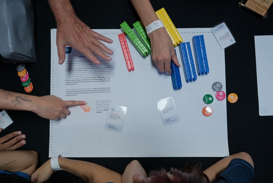 Mãos interagindo com tabuleiro de RPG sobre energias renováveis